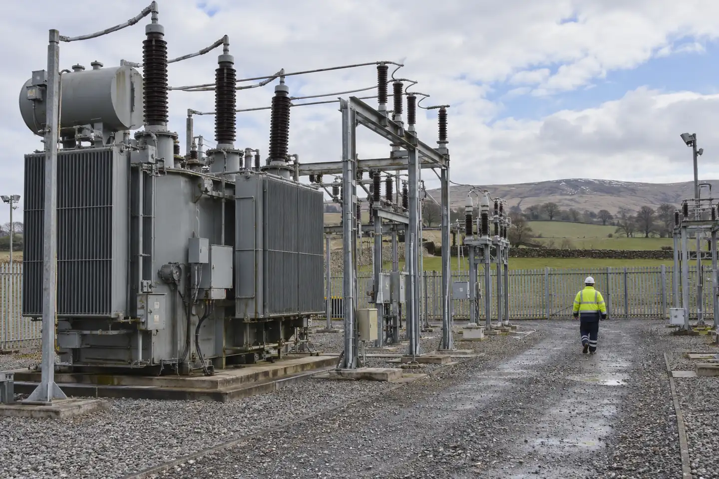 An engineer walking through an onshore electricity substation in farmland